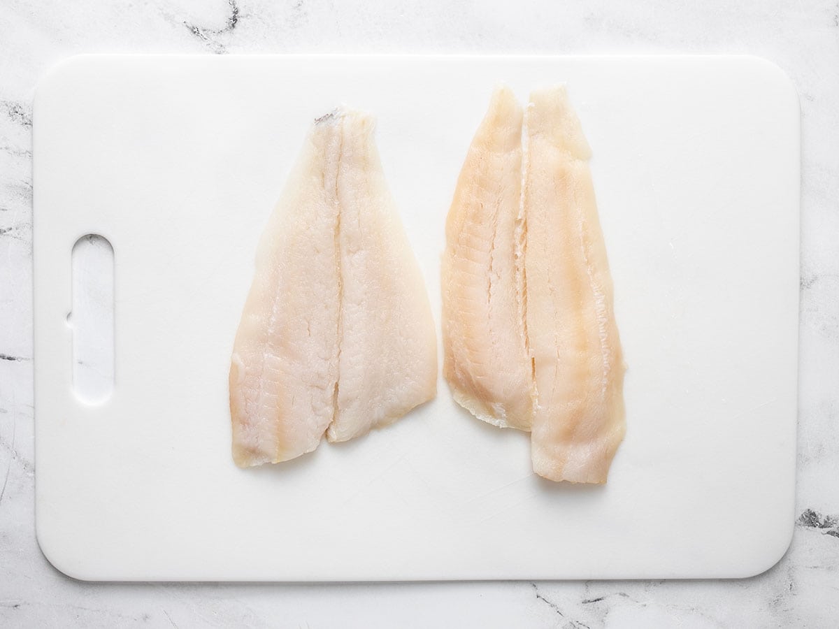 thawed flounder filets on a cutting board.