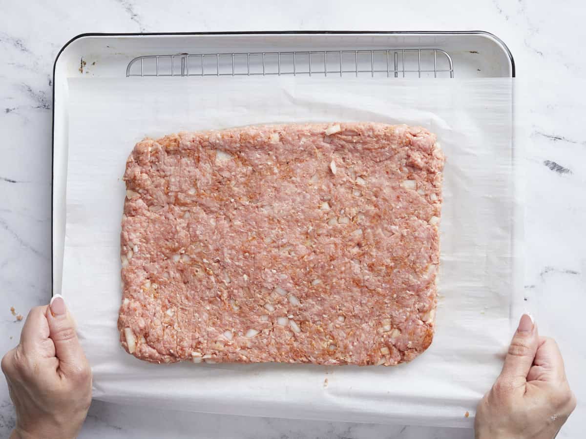 Seasoned meat mixture shaped into a rectangle on a sheet pan with parchment.
