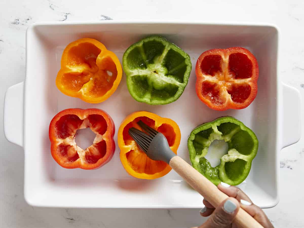 Bell peppers being brushed with olive oil.