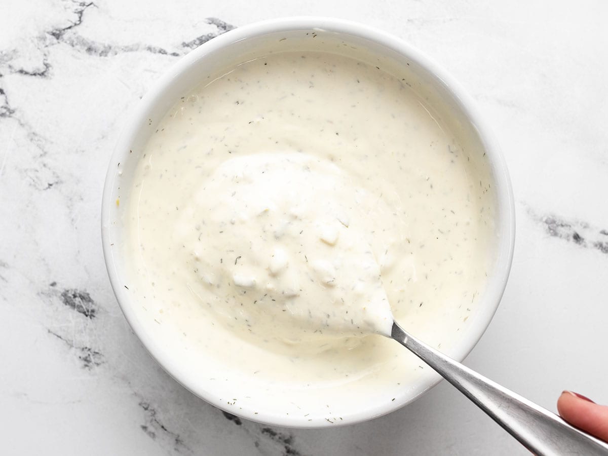 Finished tartar sauce in a bowl with a spoon.