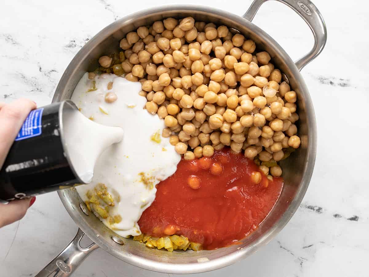 Chickpeas, tomato sauce, and coconut milk added to the skillet.