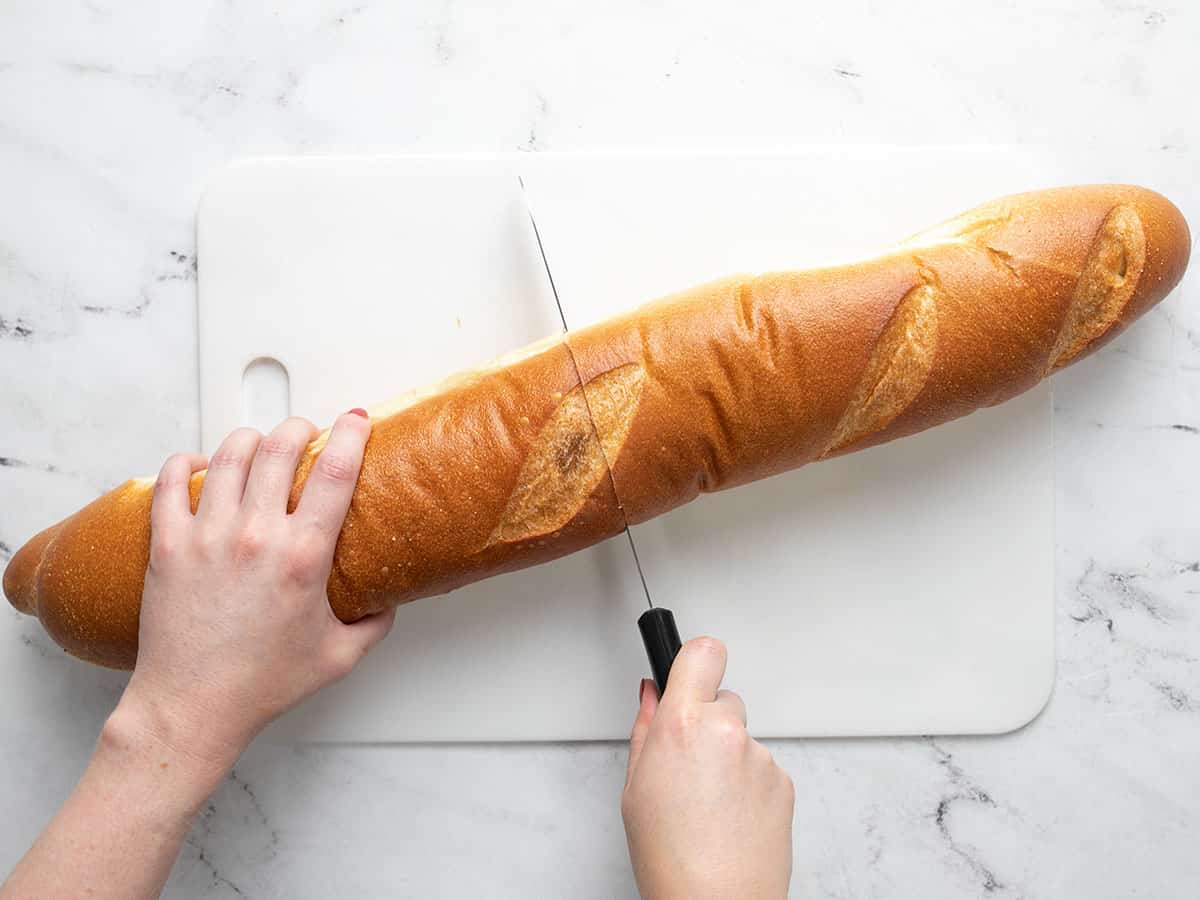 French loaf being sliced in half.