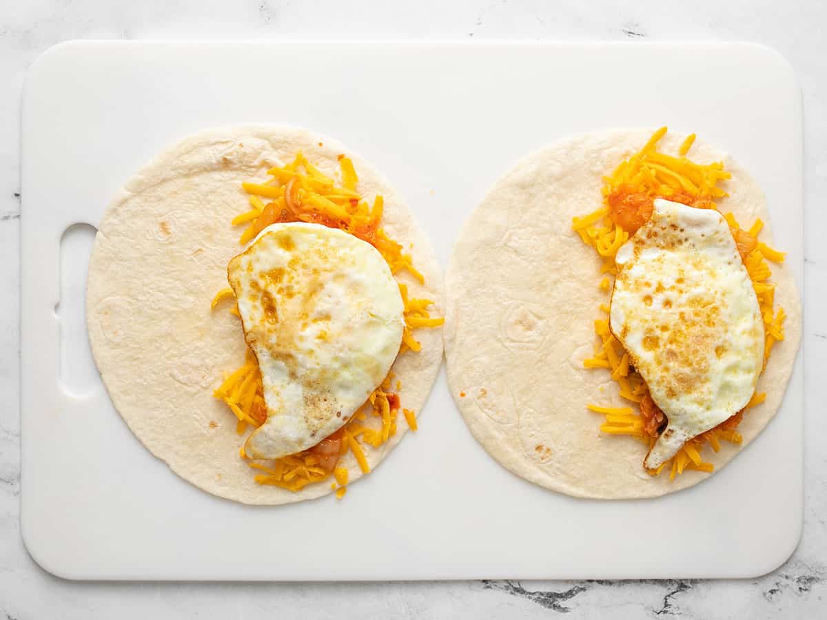 Eggs added on top of cheese and kimchi in the tortillas.