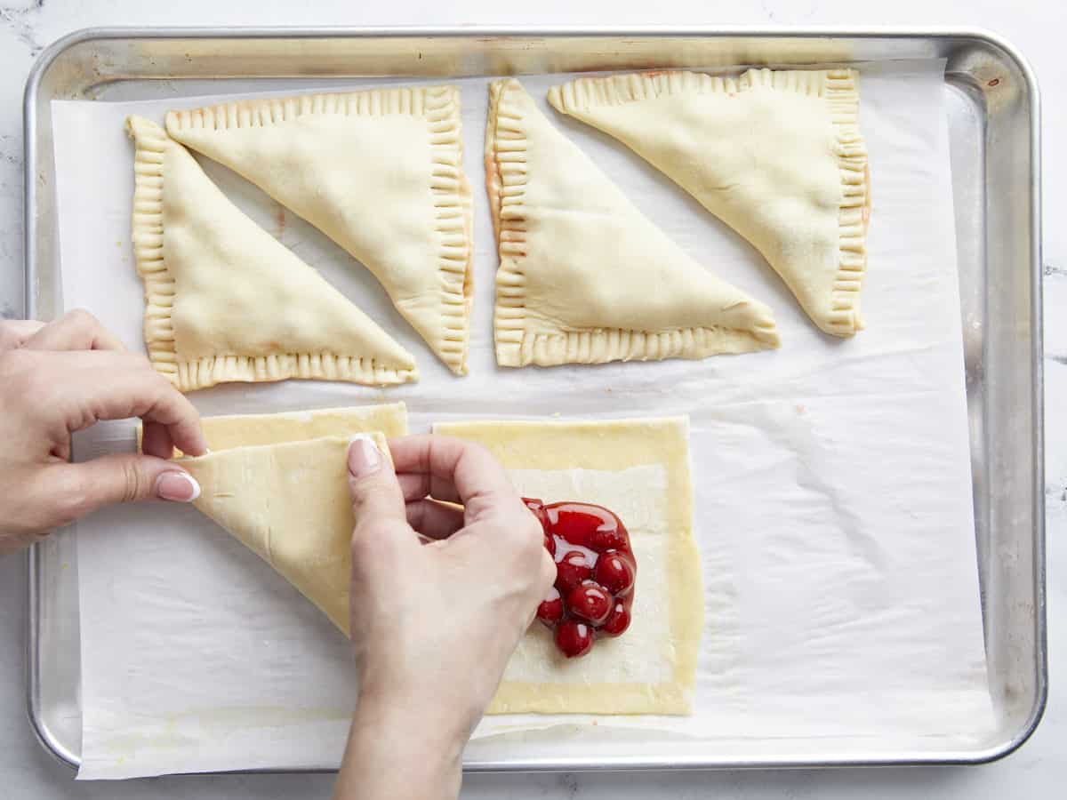 puff pastry being folded over the cherry filling.