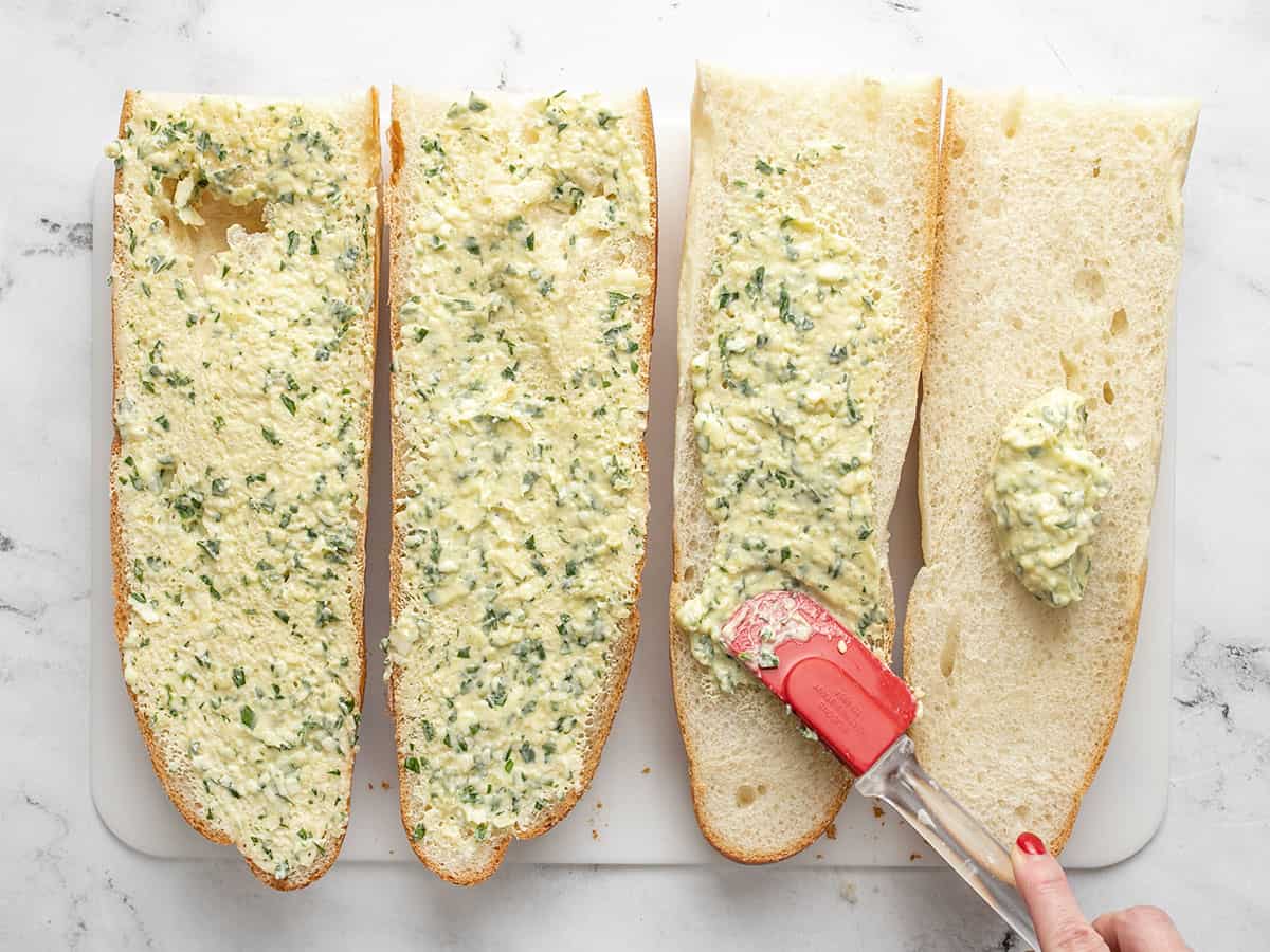 Garlic butter being spread onto French bread.