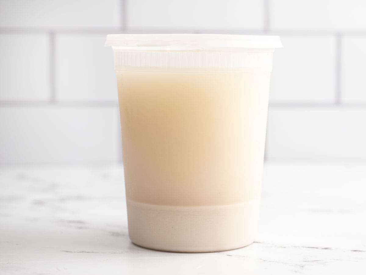 Chilled oat milk in a plastic quart container.