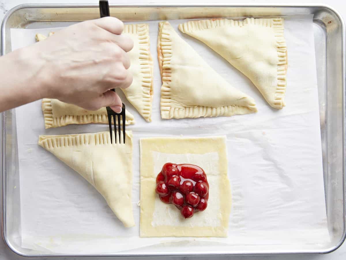 Puff pastry seams being sealed with a fork.
