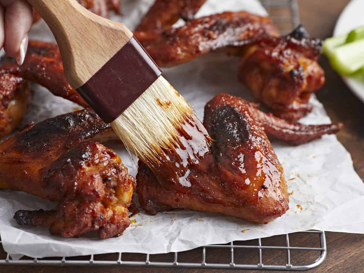 Side shot of BBQ Wings being brushed with BBQ sauce.