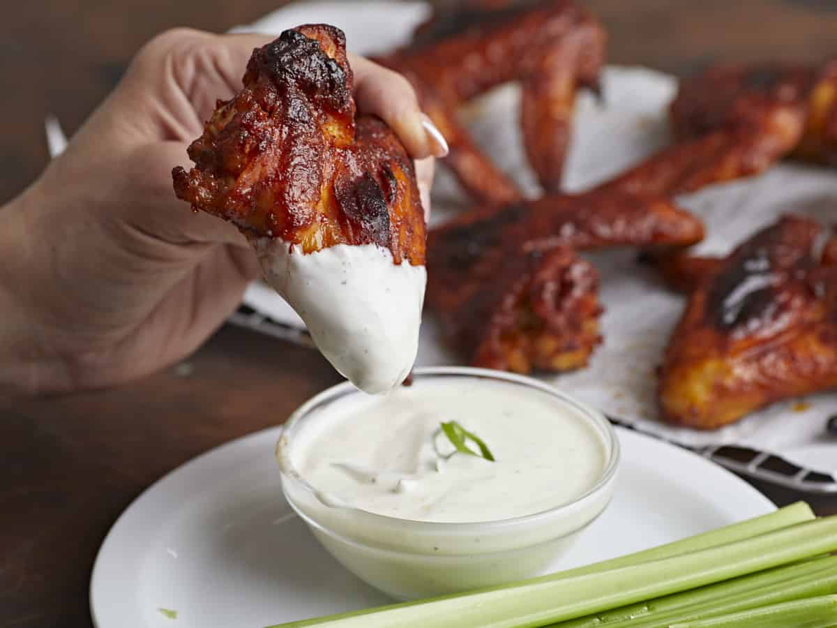 Side shot of BBQ Wing being dipped into bowl of ranch dressing.