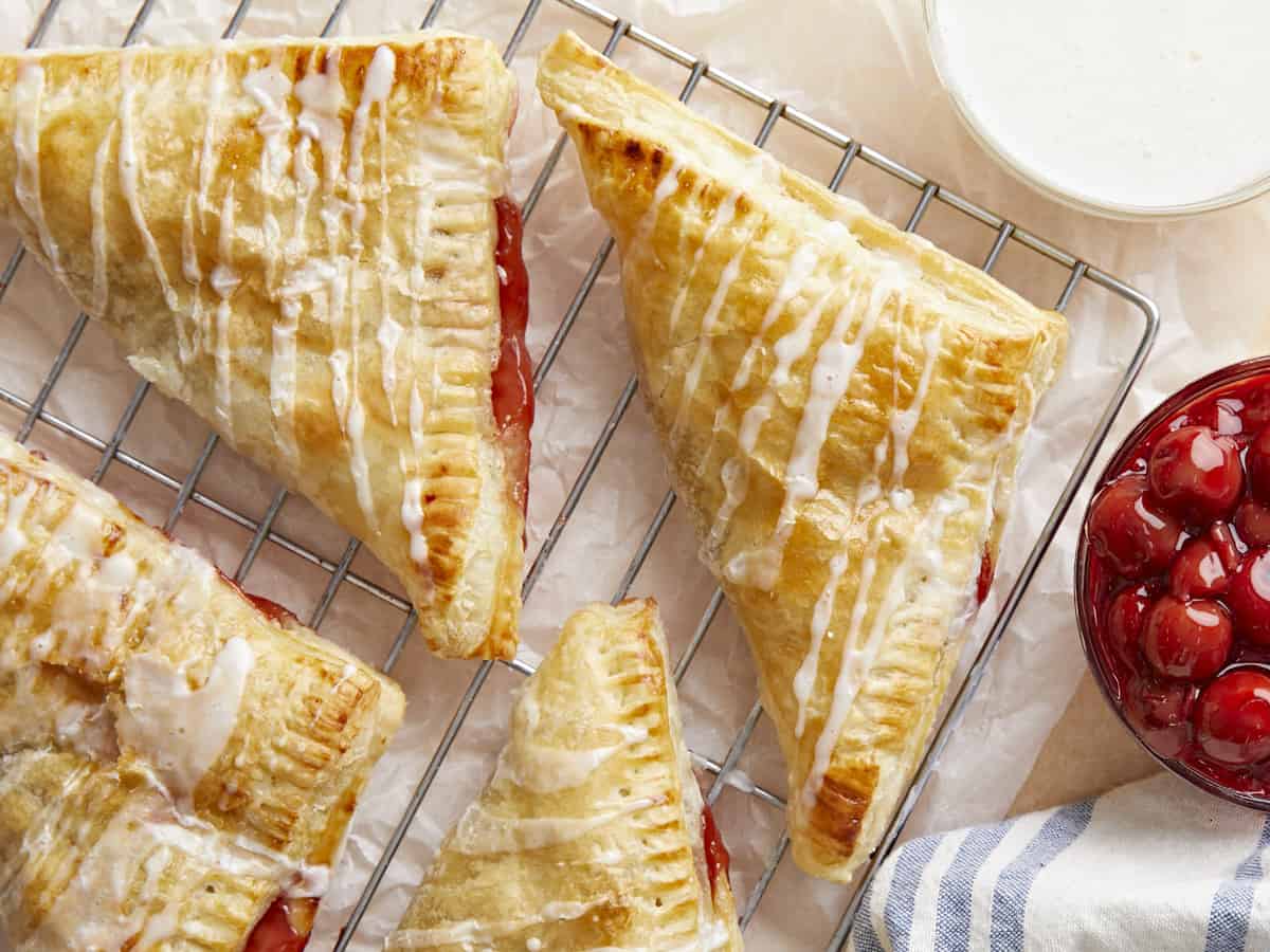 Overhead view of cherry turnovers on a wire cooling rack.