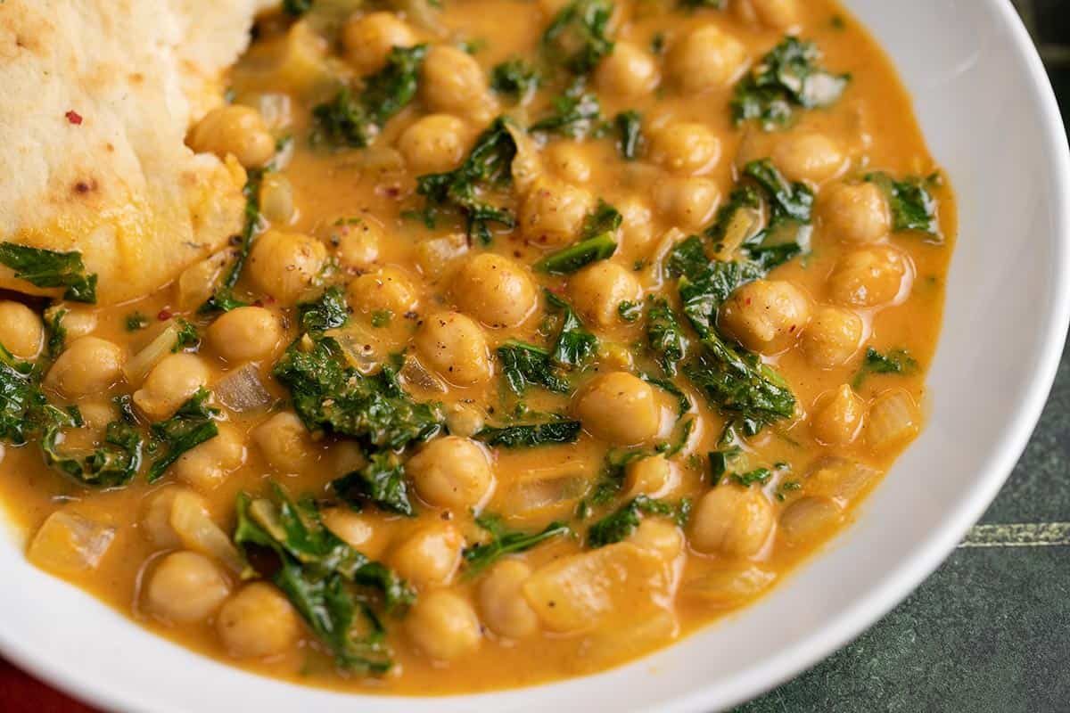 Close up side view of a bowl full of coconut curry chickpeas. 
