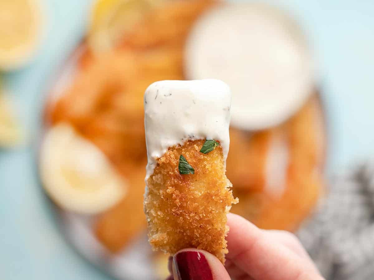 Close up of a fish stick dipped in tartar sauce.