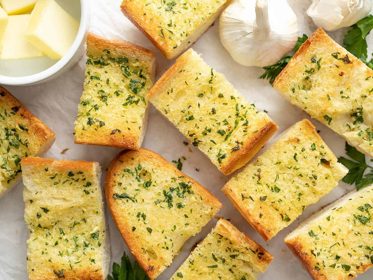Slices of homemade garlic bread spread out on a surface.