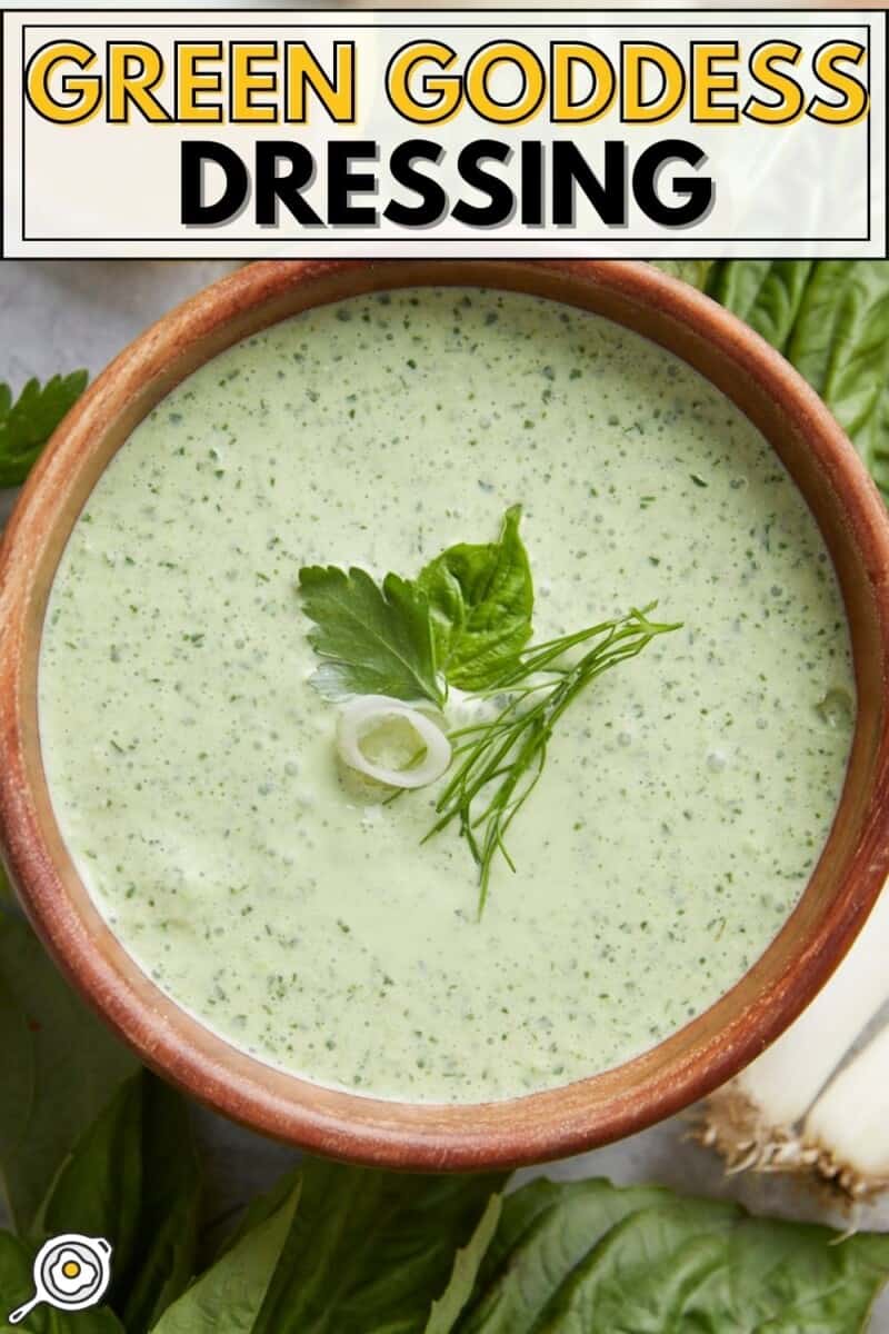 Overhead shot of Green Goddess Dressing in a wood bowl garnished with herbs.