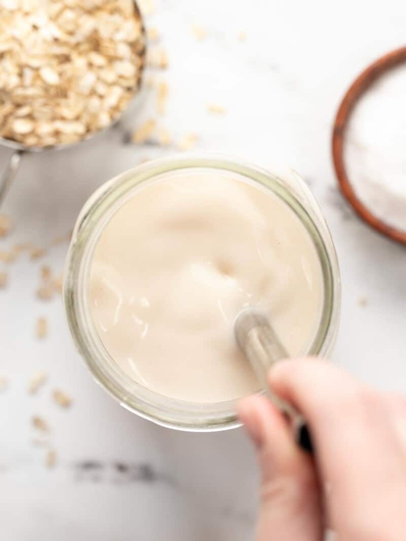 Overhead view of a jar of oat milk being stirred.