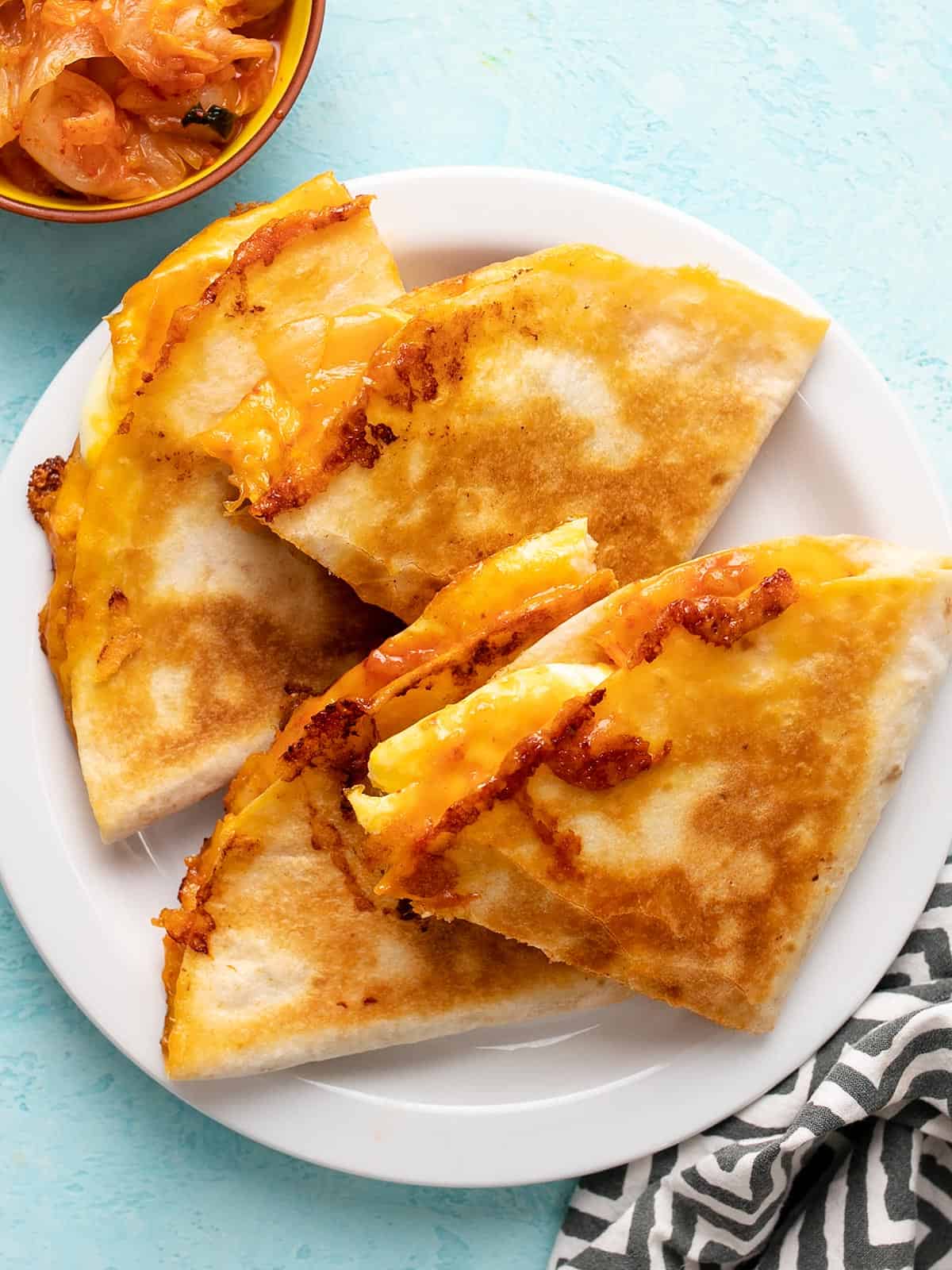 Cheese Quesadillas on a plate with a bowl of kimchi on the side.