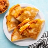 Overhead view of sliced kimchi quesadillas on a plate.