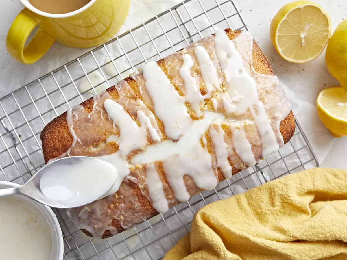 Icing being drizzled over a loaf of lemon pound cake.