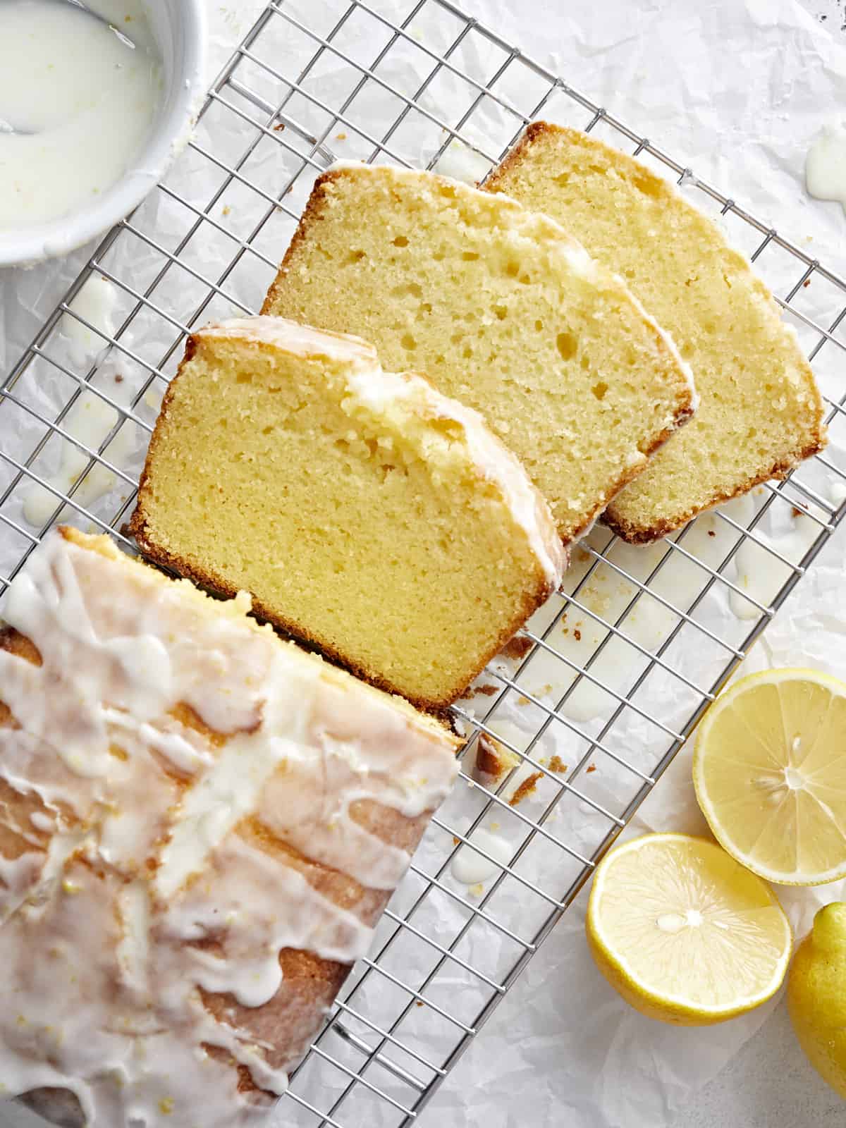Overhead view of lemon pound cake sliced on a wire cooling rack.