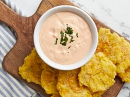 Overhead shot of Mayo ketchup in a small white bowl surrounded by tostones.