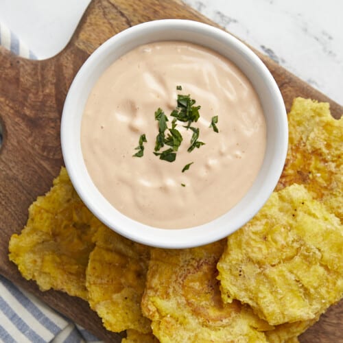 Overhead shot of Mayo ketchup in a small white bowl surrounded by tostones.