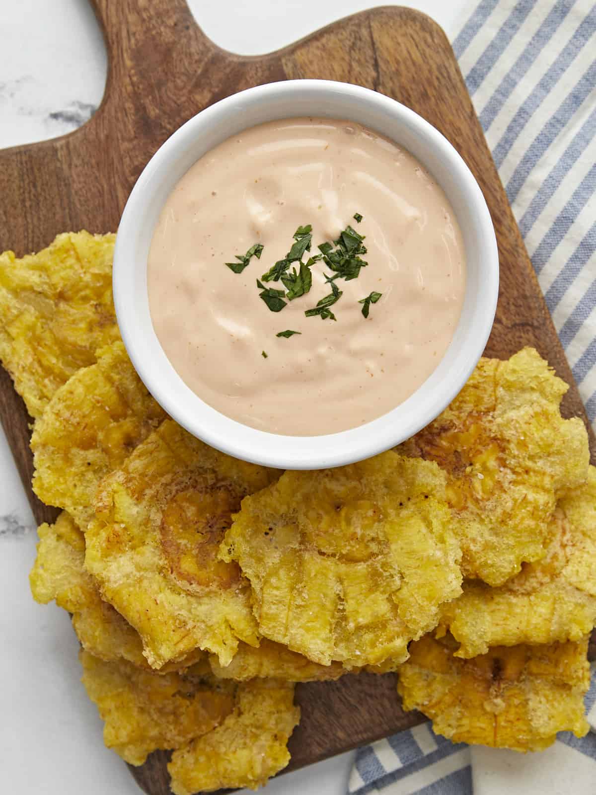 Overhead shot of Mayo ketchup in a small white bowl surrounded by tostones.