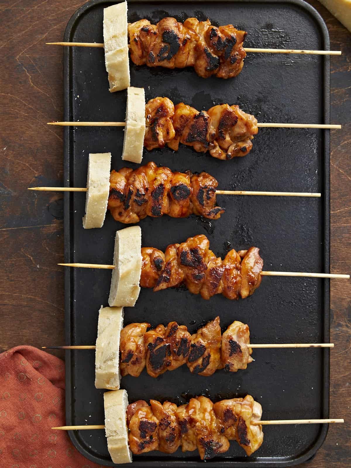 Overhead shot of Pinchos de Pollo on a black grill plate.