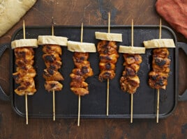 Overhead shot of Pinchos De Pollo on a black grill plate.