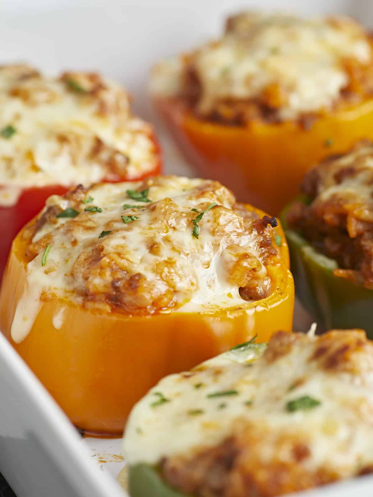 Close up side view of stuffed bell peppers in a casserole dish garnished with parsley.