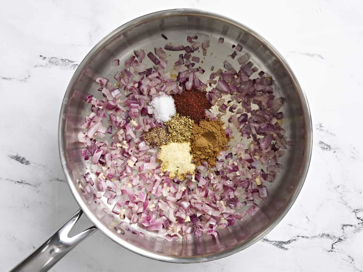 Diced red onion, garlic, and spices in a skillet.