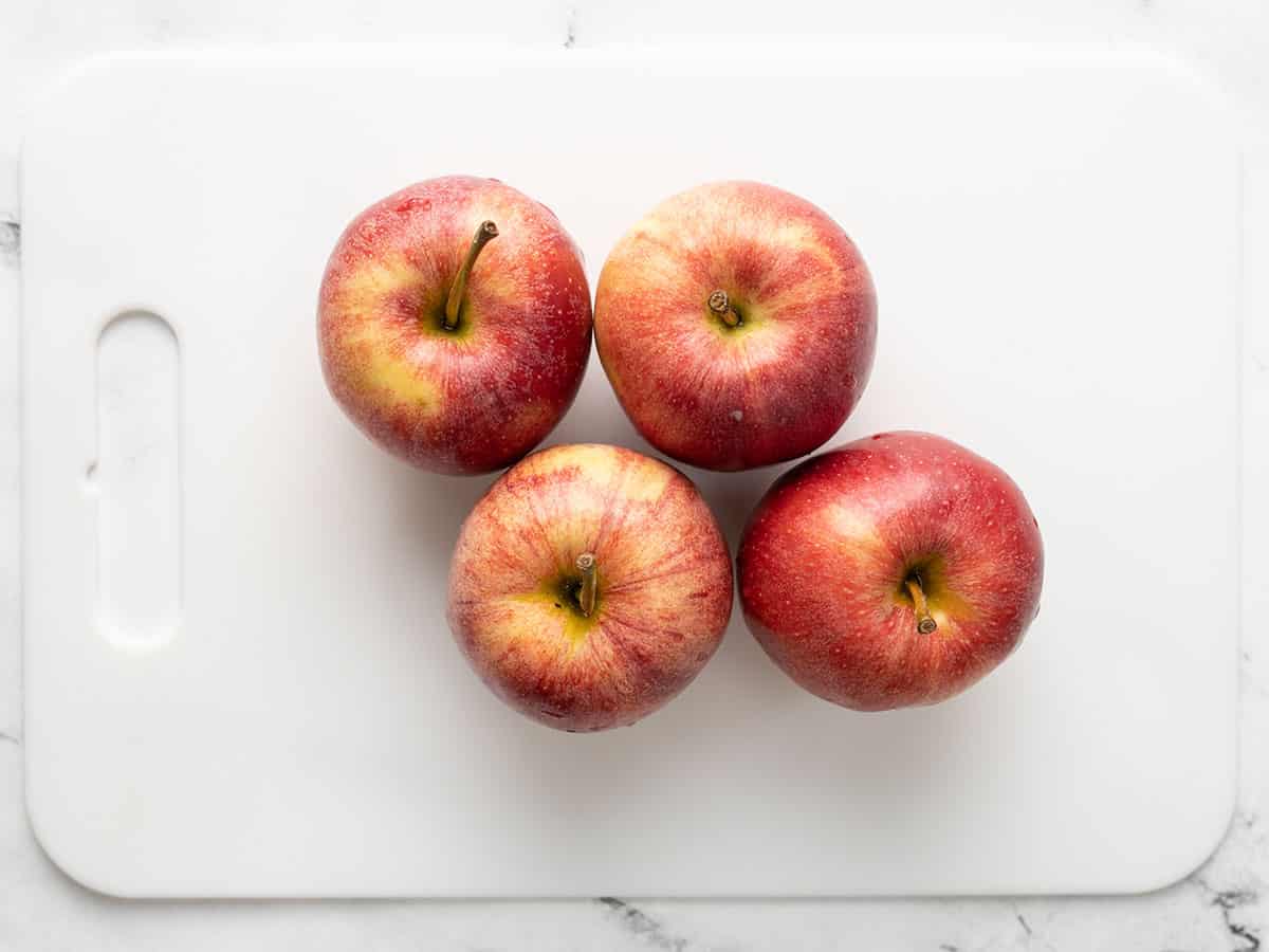 Four apples on a cutting board. 