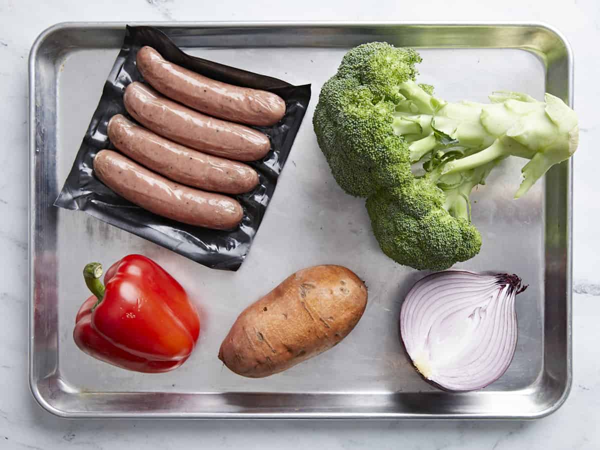Ingredients for sheet pan chicken sausage dinner on a baking sheet