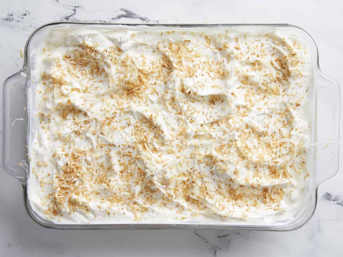 Coconut cream pie bars topped with whipped cream and toasted coconut. 