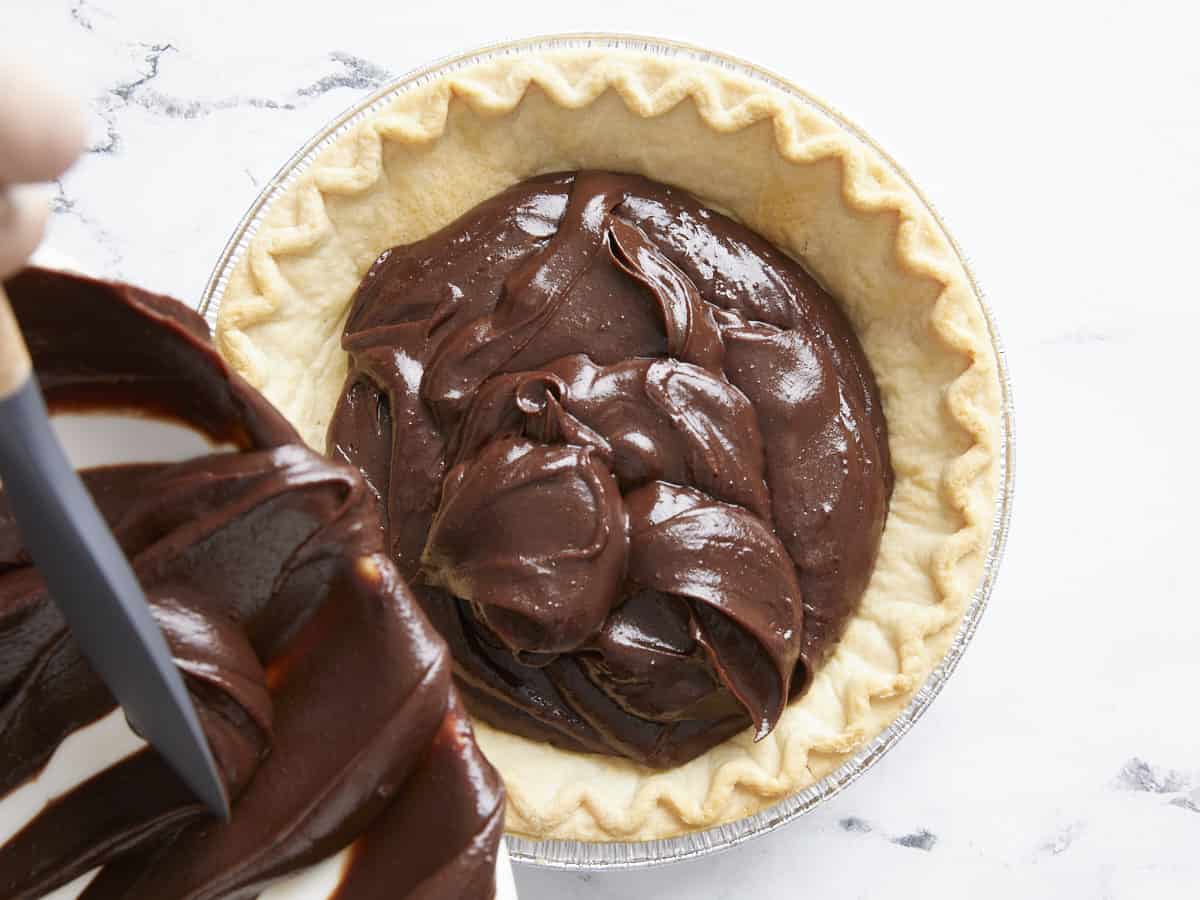 Chocolate cream mixture being poured into the pie crust. 