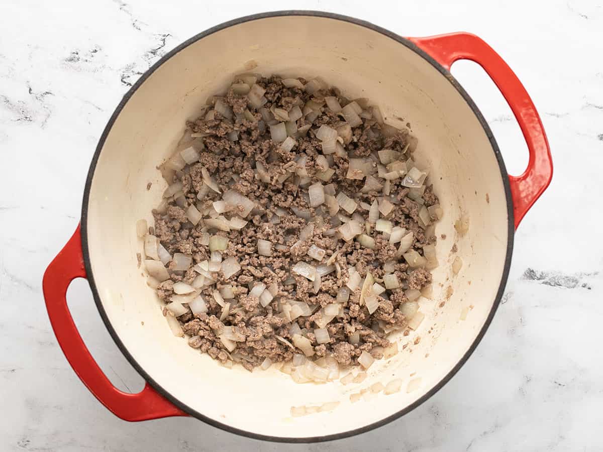 Browned beef in the pot with garlic and onions.