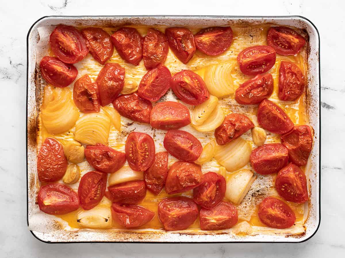 Roasted tomatoes, onions, and garlic on the sheet pan. 
