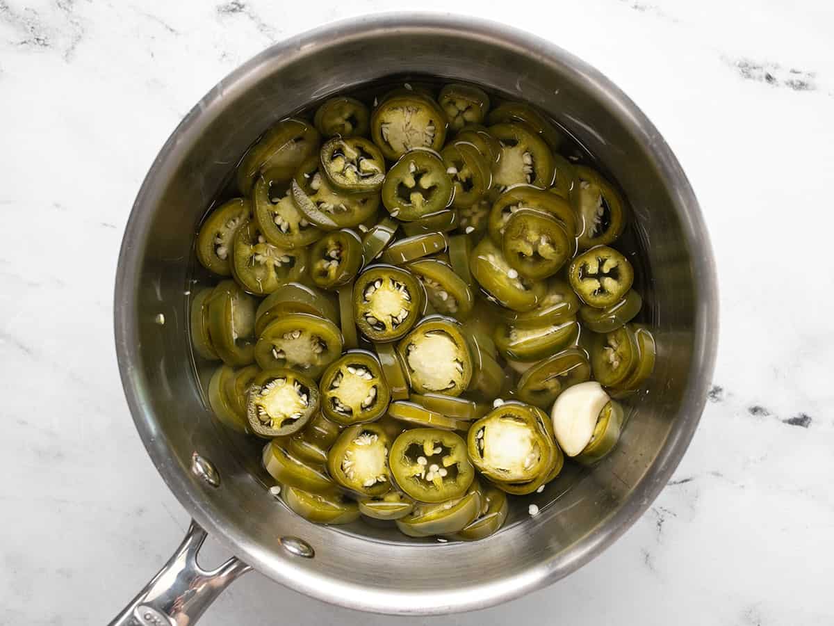 Pickled jalapeños in the brine in the sauce pot.