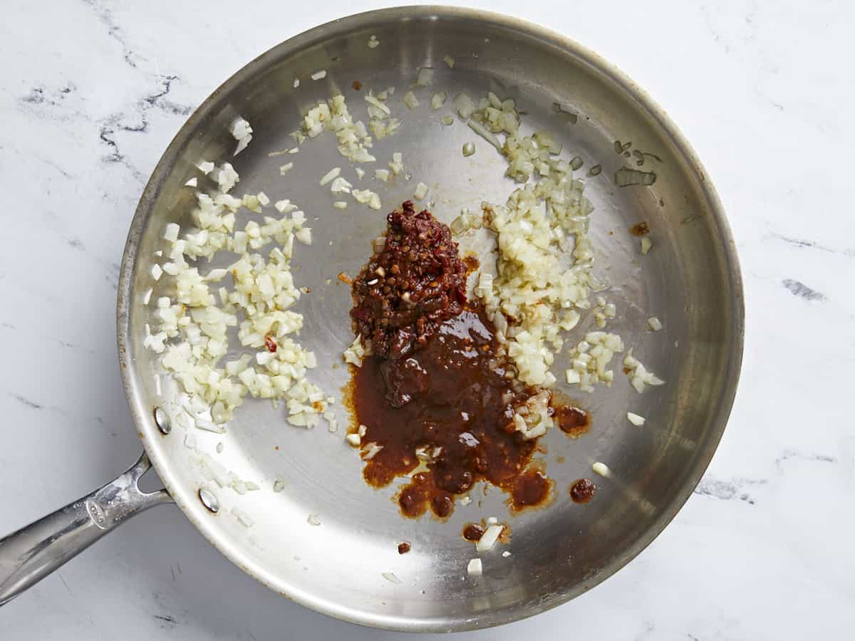 Chipotle peppers added to the skillet with onion and garlic.