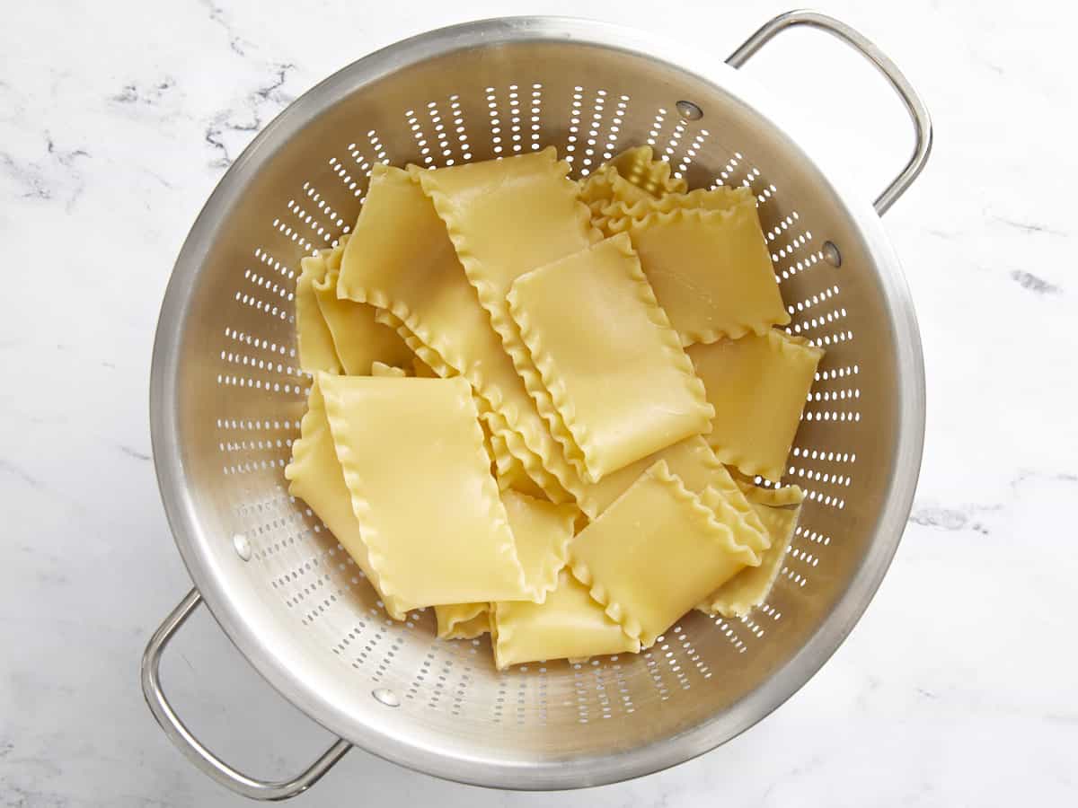 Boiled lasagna noodles in a colander.