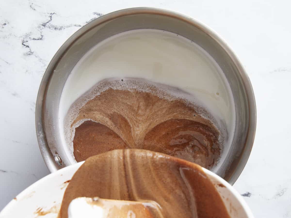 Chocolate mixture being poured into hot milk. 