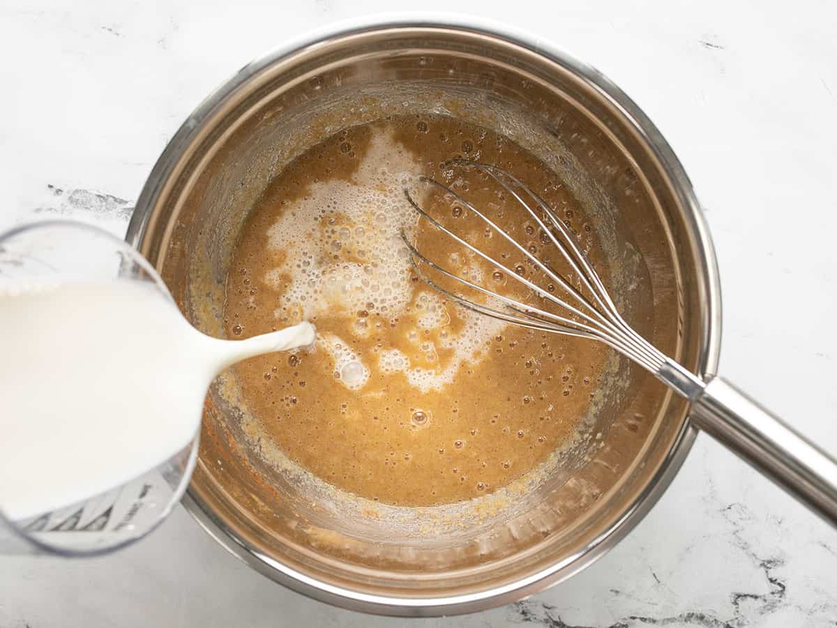 Milk being poured into the bowl of applesauce mixture.