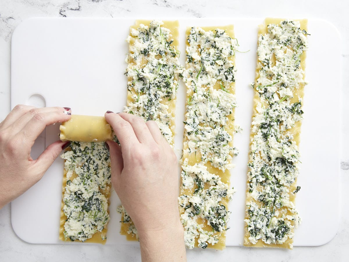 Lasagna noodles being filled and rolled.