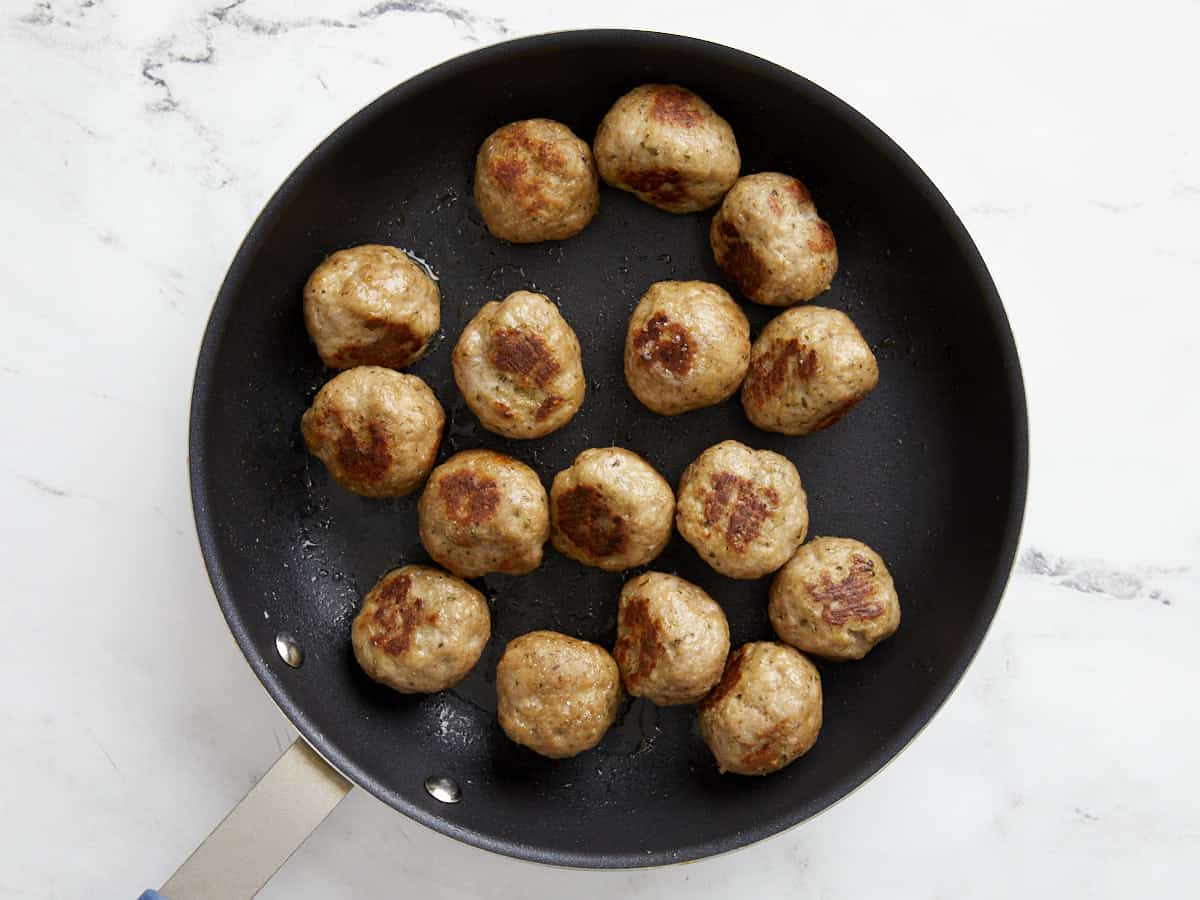 Turkey meatballs browned in a skillet. 