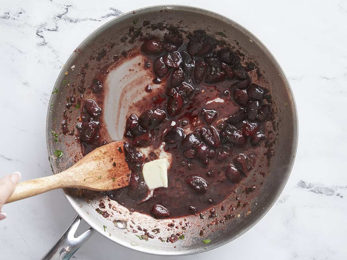 Butter added to the cherry red wine sauce in the skillet.