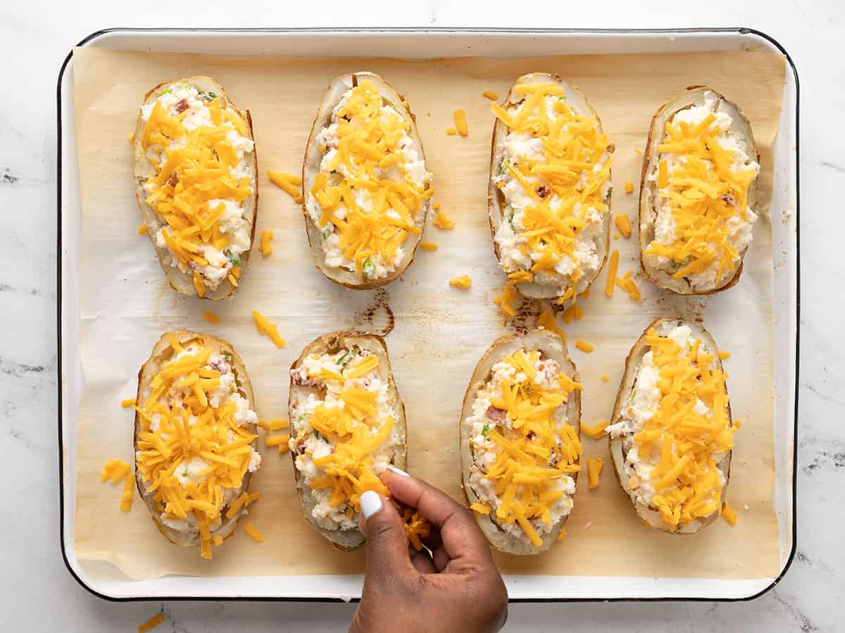 Potato skins filled with mashed potato mixture and topped with more shredded cheddar cheese.