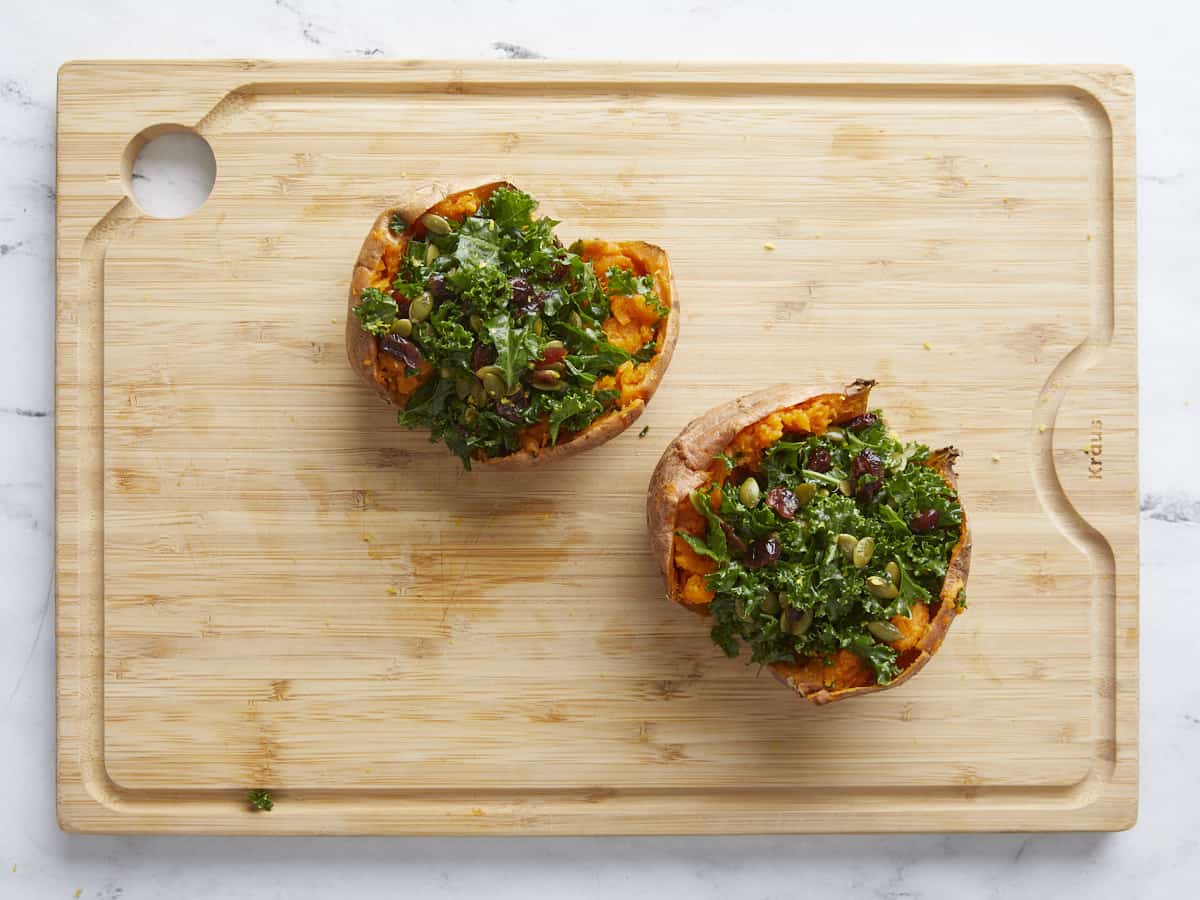 Sweet potatoes stuffed with kale on a wooden cutting board. 