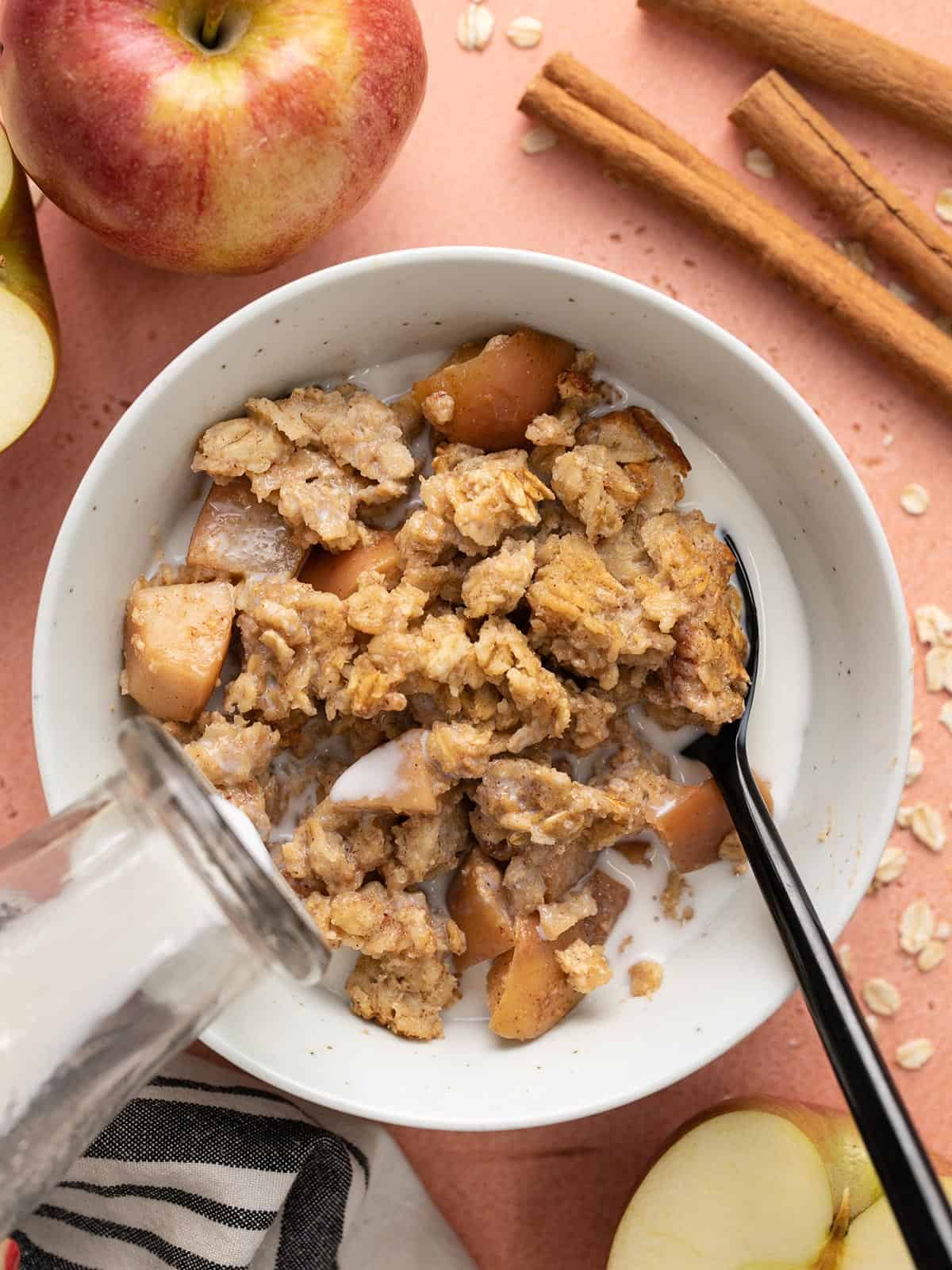 Milk being poured into a bowl of apple cinnamon baked oatmeal.