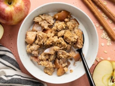 A bowl full of apple cinnamon baked oatmeal with milk.
