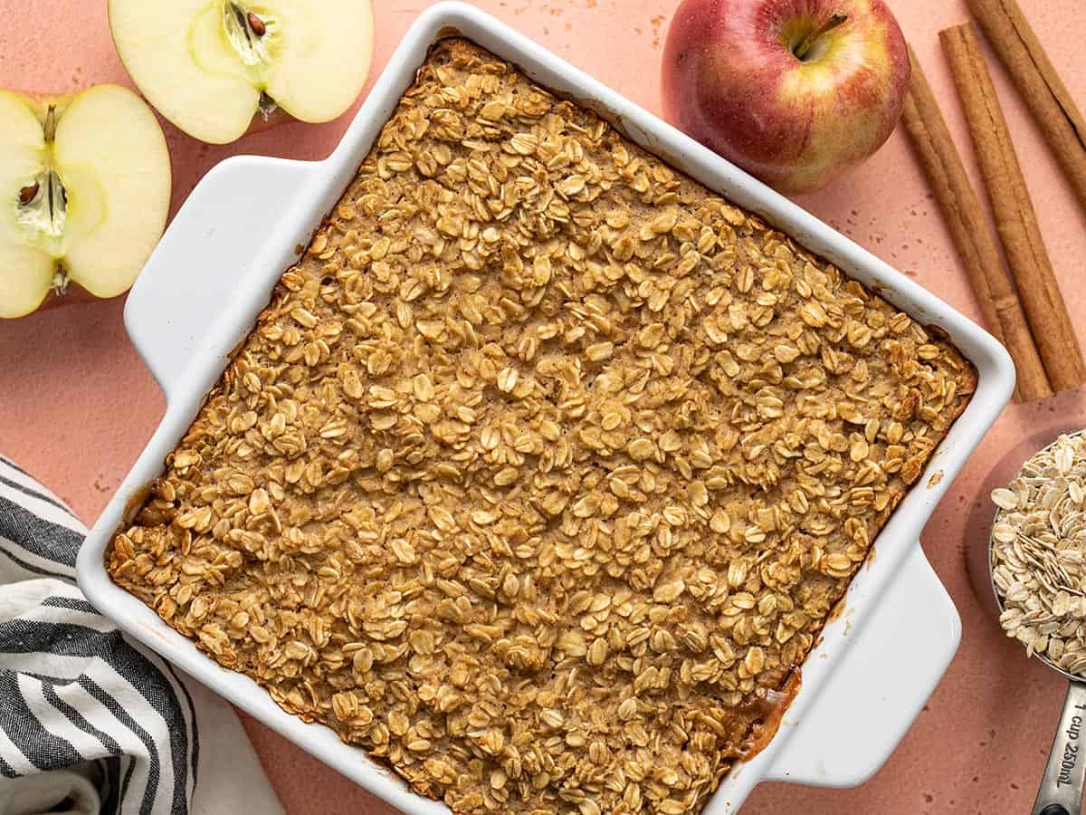 Overhead view of a casserole dish full of apple cinnamon baked oatmeal with ingredients on the sides. 