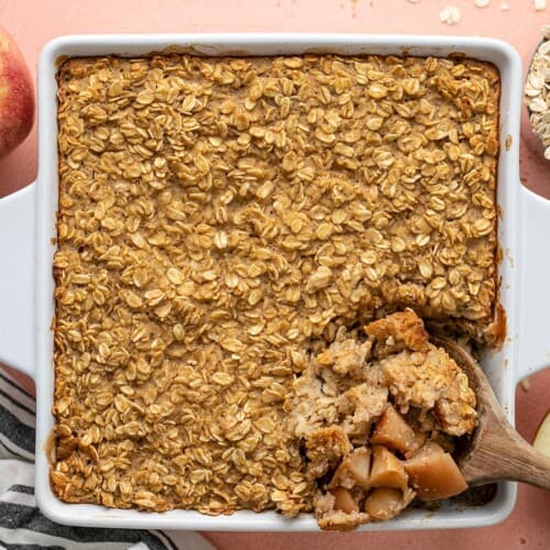 Overhead view of a casserole dish of apple cinnamon baked oatmeal with the corner being scooped out.